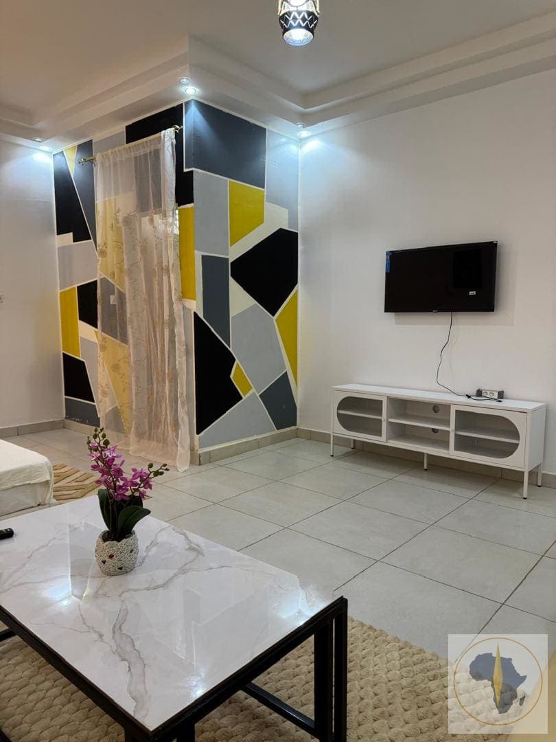 chambre climatisée avec un salon et une salle de bain — Appartement en location saisonnière à Louga — OroSira Immo